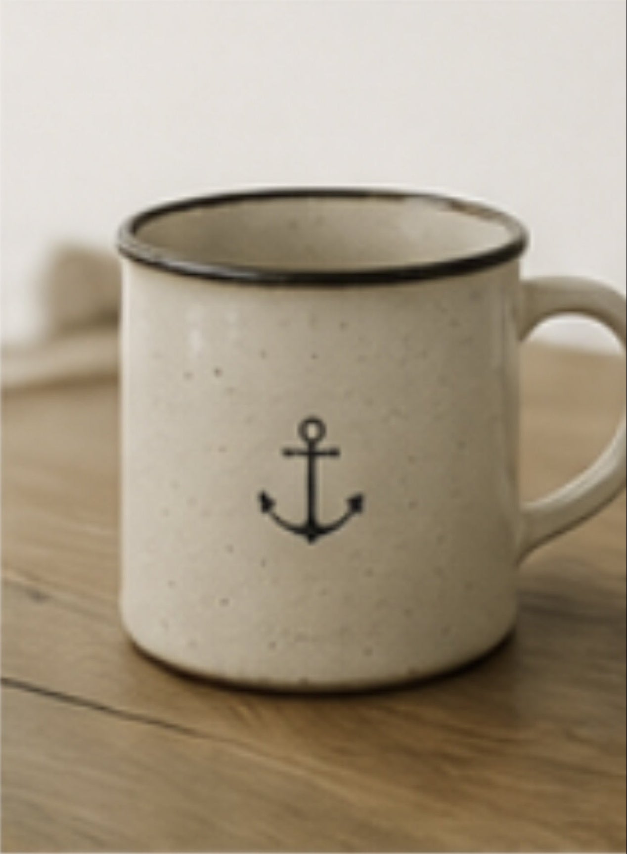 White mug with black anchor design on a wooden surface, with 'Shop Now' text above.